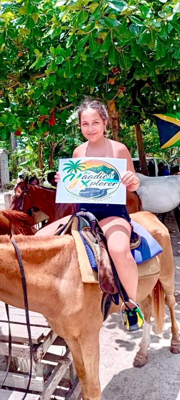 A smiling guest on horseback holding The Yaadie Xplorer sign